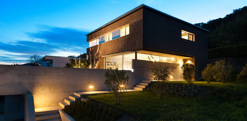 A large, modern, well-lit home at dusk
